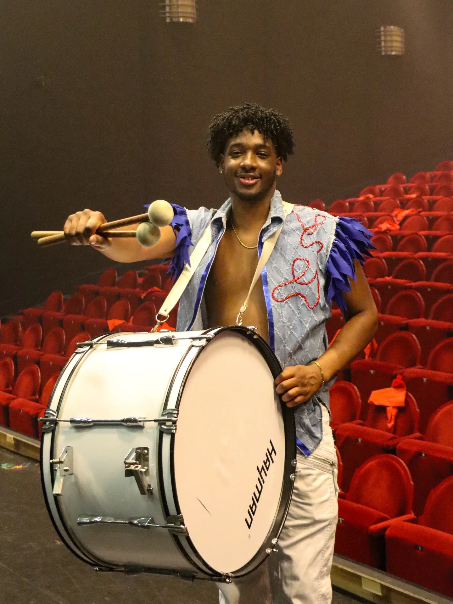 Drummer met een witte basdrum in een theaterzaal met rode stoelen