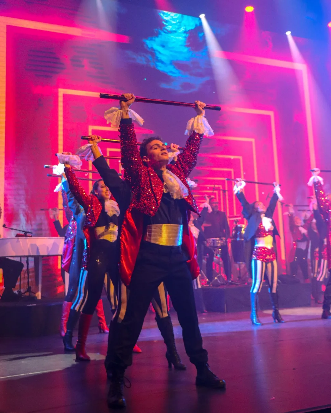 Dansers in een krachtige pose op het podium in roze en paars licht