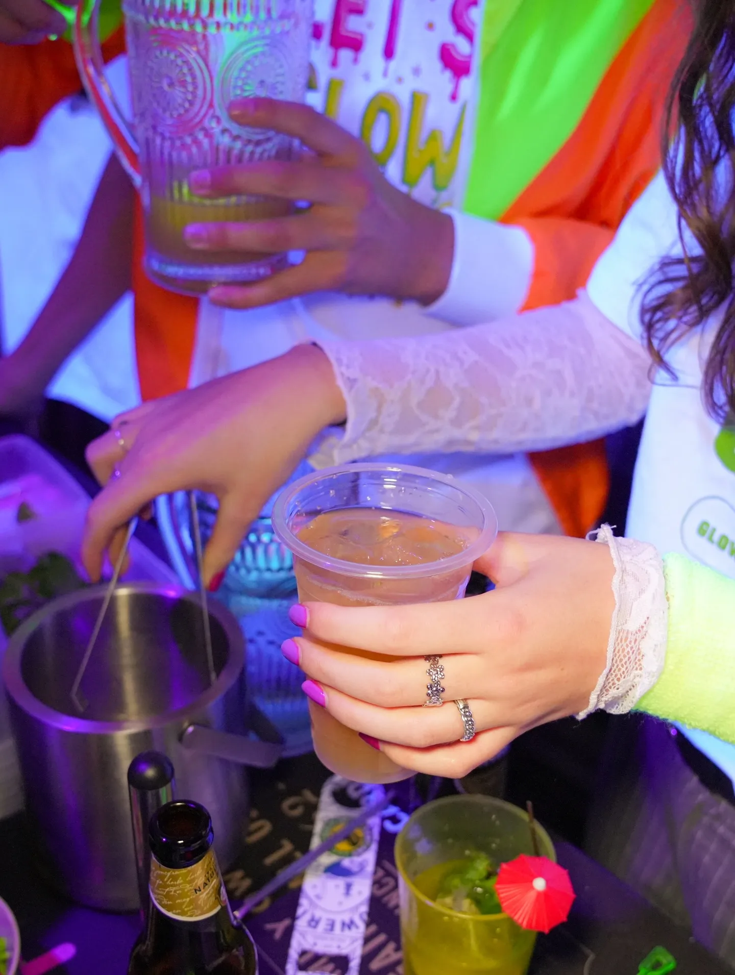 Close-up van glazen en handen met neonarmbandjes op een feest