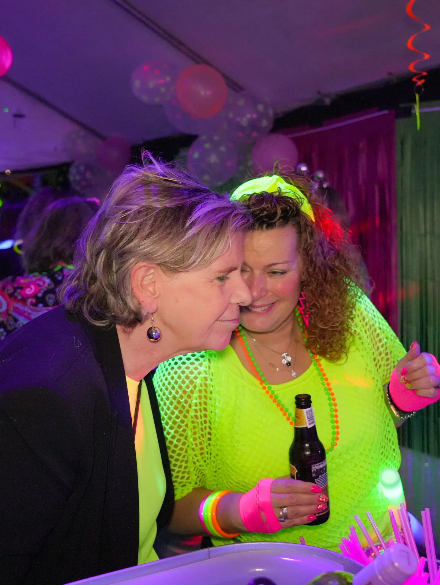 Twee feestgangers in neonkleuren lachen samen