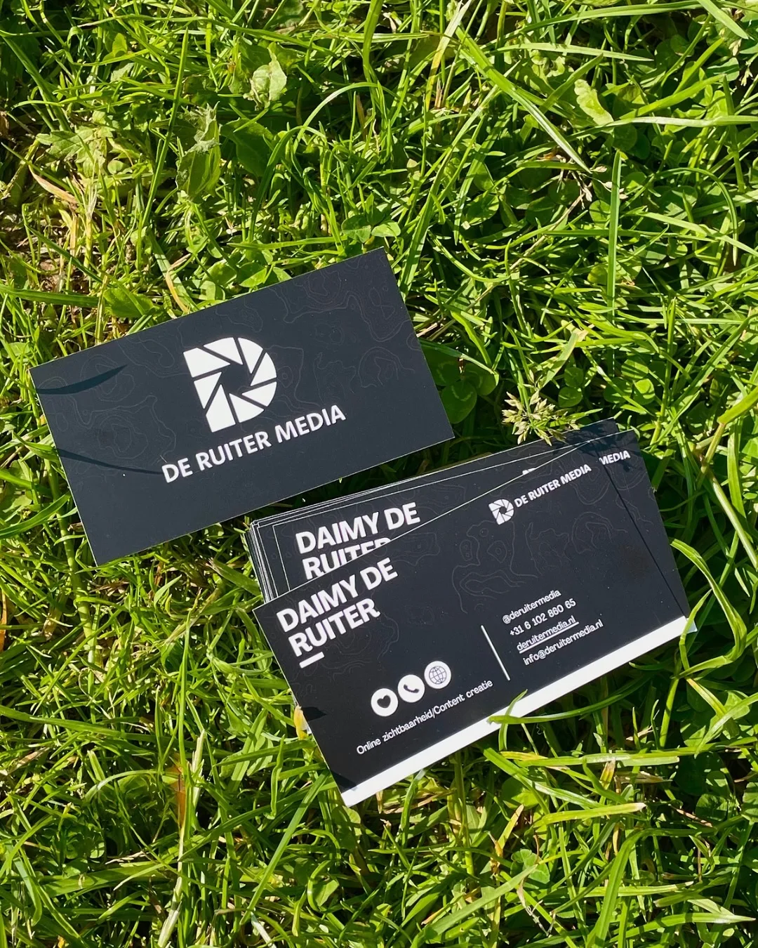 Zwarte visitekaartjes van De Ruiter Media op het gras
